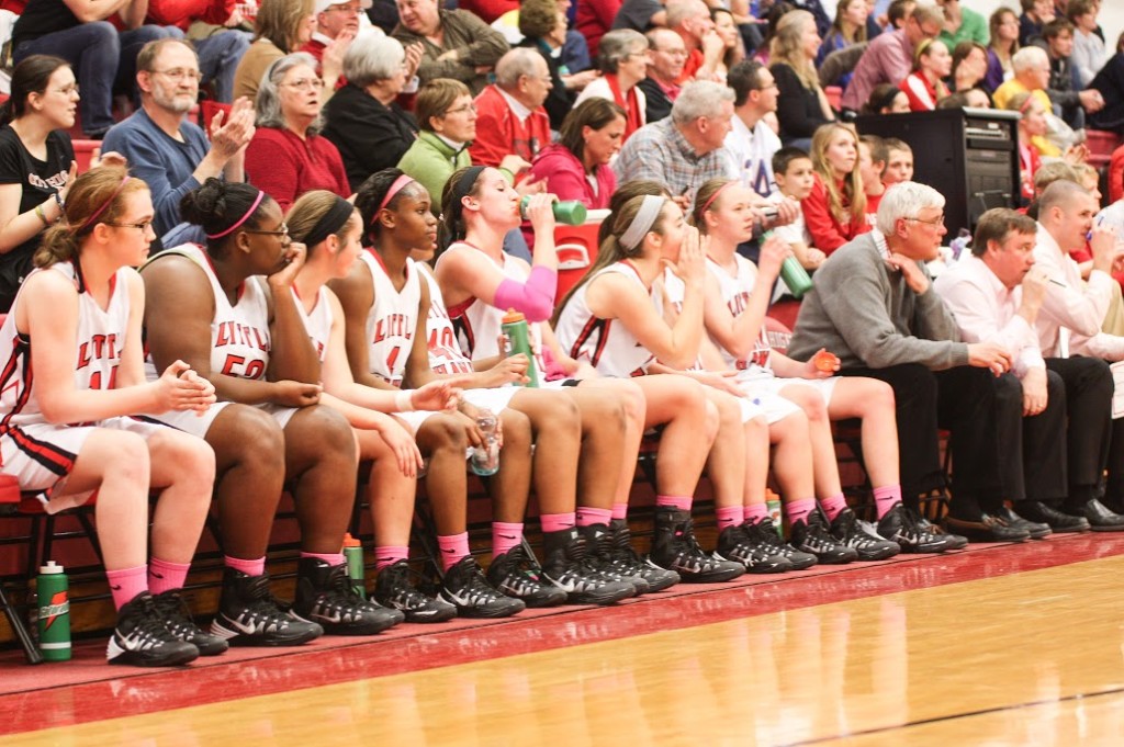 The Girls Basketball team watches and cheers for each other in their pink socks.