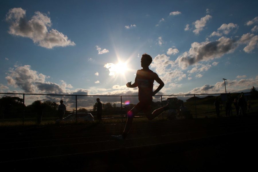 A City High runner runs through the first turn while being silhouetted by the sun on Thursday, May 12th, 2016. 