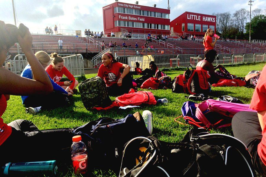 City+High+track+athletes+sitting+on+the+turf+while+waiting+for+their+meet+to+start.