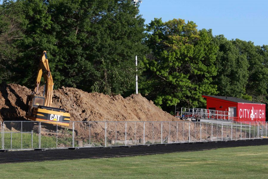 A construction worker operates a backhoe to dig footings on the east side guest bleachers of City Highs Frank Bates Field in Iowa City on Thursday, June 16, 2016.