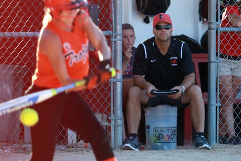 City High head coach Jeff Koenig watches from the dugout as a Trojan player swings at a pitch during the Little Hawks second game against Waterloo East at City High on Thursday, June 16, 2016.