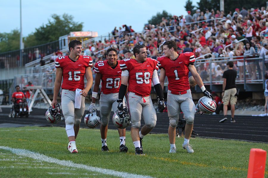Nate Wieland 17 (#15), Naeem Smith 17 (#20), Joey Schnoebelen 17 (#58), and Brock Hunger 17 (#1) chat on the sidelines before the game.