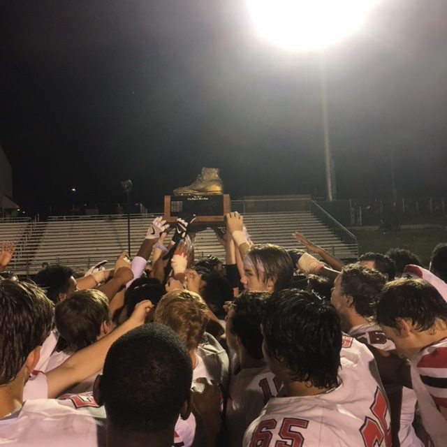 City High players celebrate by holding up the Boot after beating West High