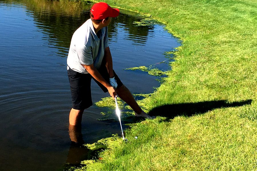 A City High golfer hits the ball from the water during the district meet. 