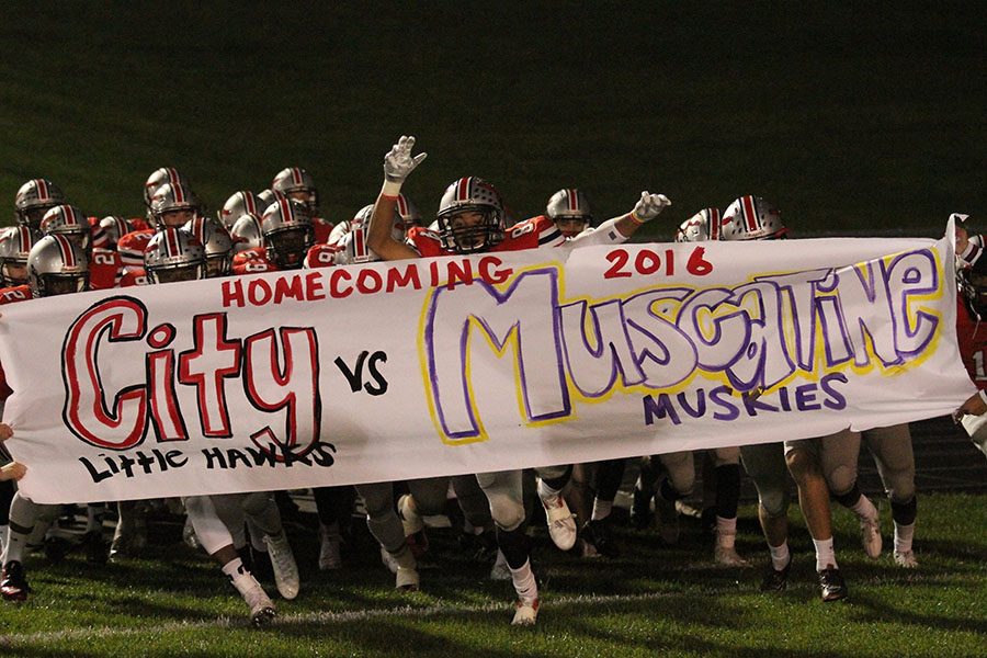 Zach Jones 18 runs through the Homecoming football banner on Friday against the Muscatine Muskies.