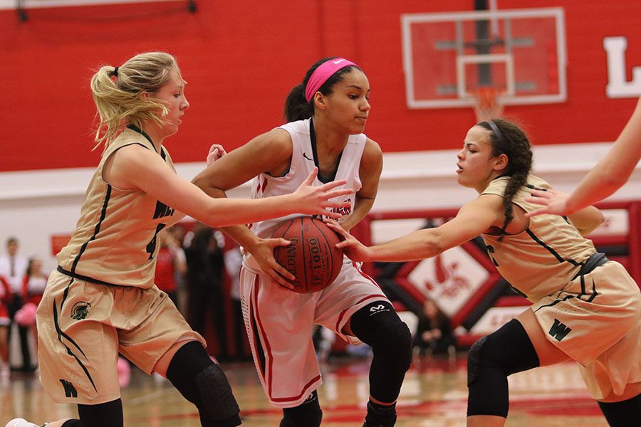 Rose Nkumu 20 is defended by two West High players. 