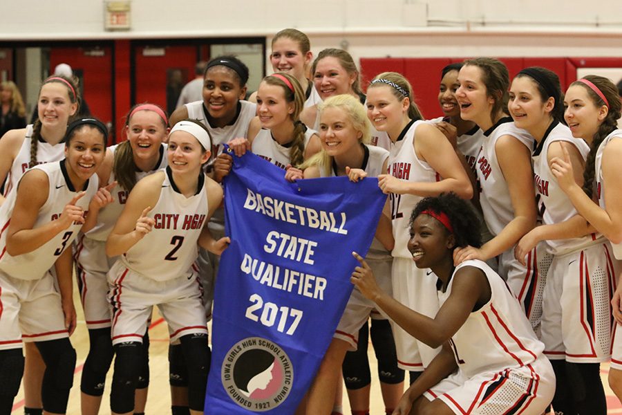 The+City+High+girls+basketball+team+poses+with+the+state+qualification+banner+after+defeating+the+Ankeny+Centennial+Jaguars+48-32.+