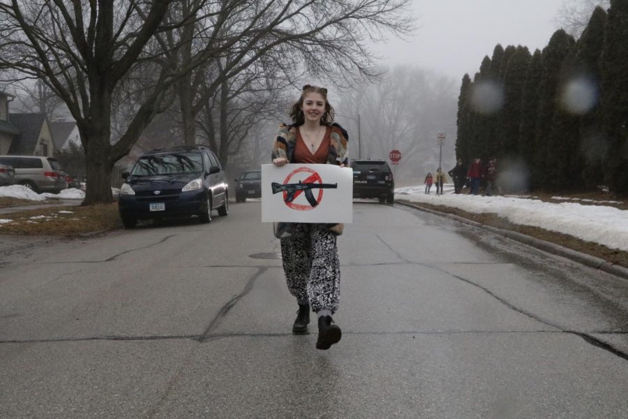 Ruby Anderson 19 leaves school with a homemade poster as the police escorts follower her down the street