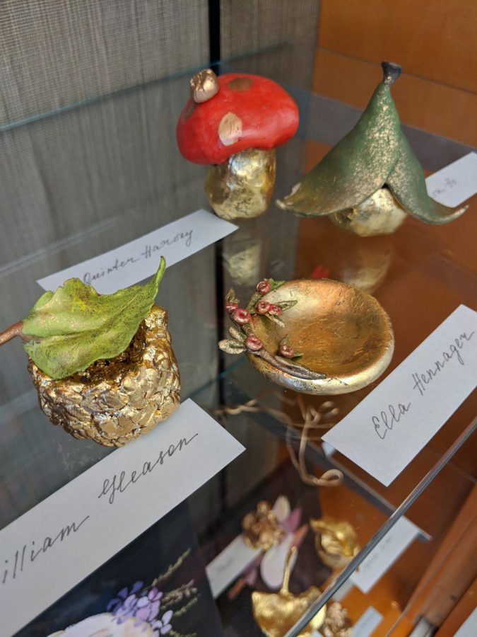 Hand-sculpted clay boxes with gold foil with paint displayed at a public library art exhibition for students in Iowa City.