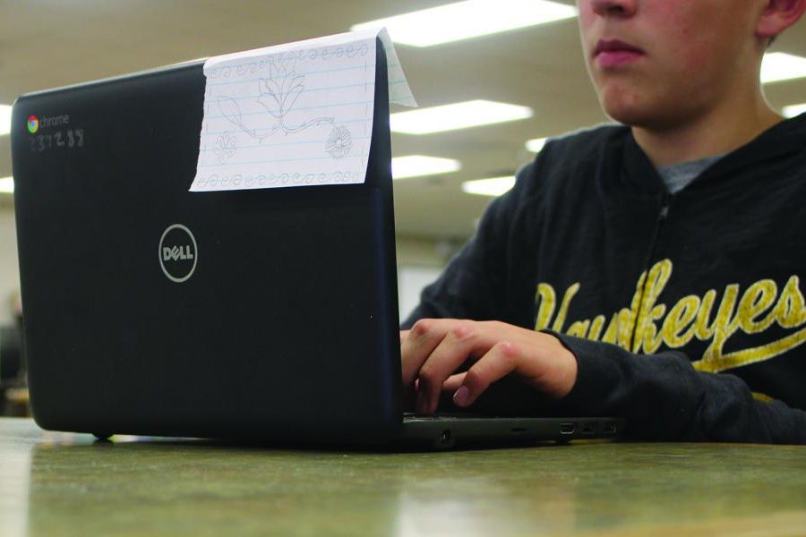 Patrick Sarsfield 22 using his Chromebook in the library.