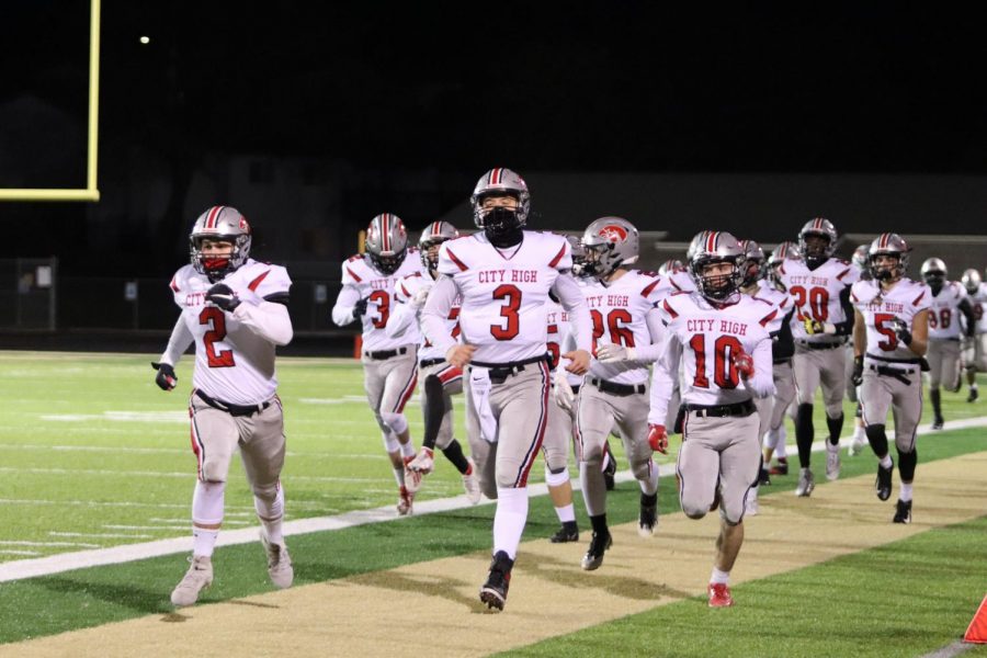 The City High football team runs onto the field before their game against West High on Friday night. 