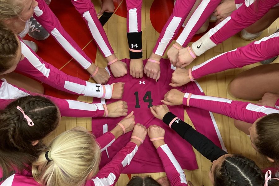 The City High volleyball team holds their hands in a circle over teammate Emma Nugents jersey. Joslyn Becker 21 had bracelets made with Emma Nugent and We play for 14 on them, which she gave to her teammates.