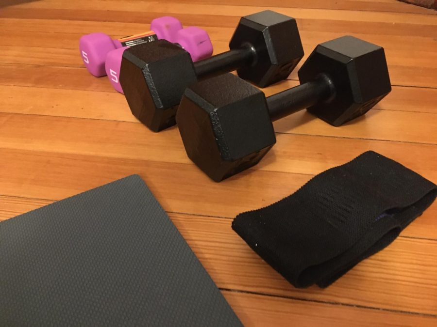 Four weights, a resistance band, and an exercise mat lying on the ground. These are all equipment that can be used for exercise during quarantine