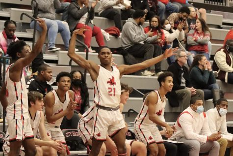 Jovan Harris 22 celebrates a teammate making a three pointer at the game against Muscatine