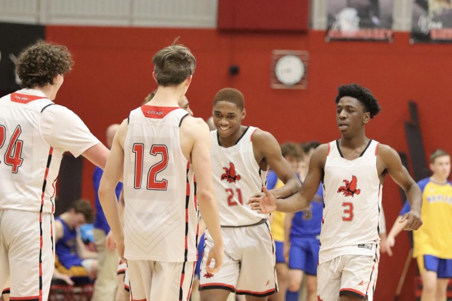 Jovan Harris '22 and David Pope '22 celebrate with teammates in the 4th quarter against Wahlert Catholic. 