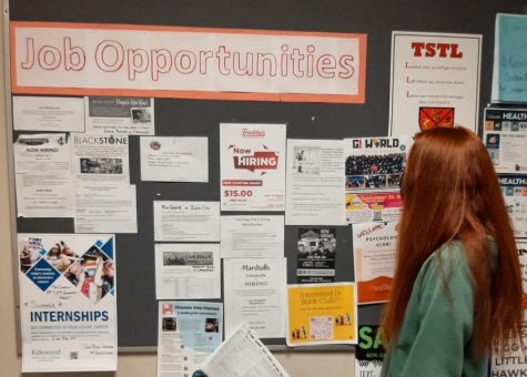 A student observes job hiring offers at various positions on the Job Opportunities Bulletin Board near the Main Foyer of City High School.