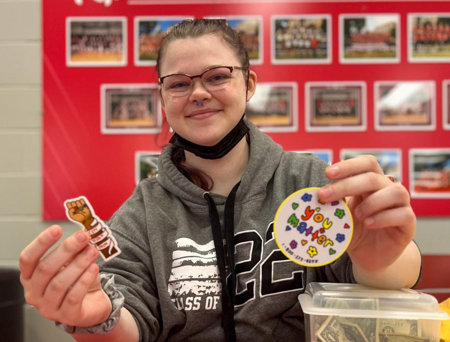 Alina Alberhasky 22 poses with the stickers being sold.  City High Student Andrea Lopez was the designer of the sticker on the left.  