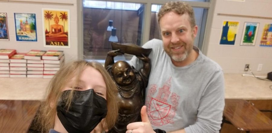 Mr. Schumann poses with a Buddha statue in the World History classroom. 