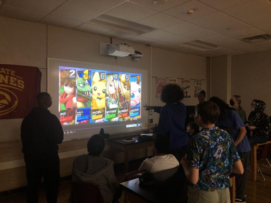 Video Game Club members gather around as they play Mario.