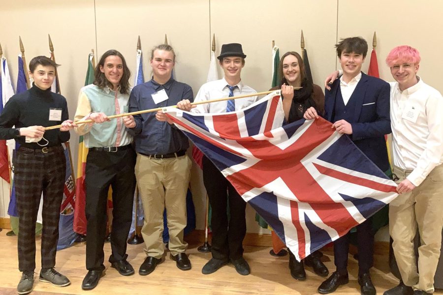 Model+UN+students+hold+up+the+UK+flag+representing+their+country+at+the+2022+March+conference.