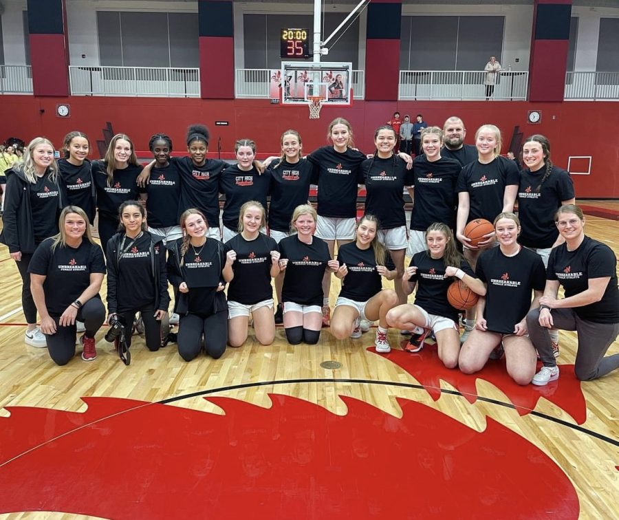City High Girls Basketball poses for a photo wearing their Unbreakable Female Athlete warm up shirts. 