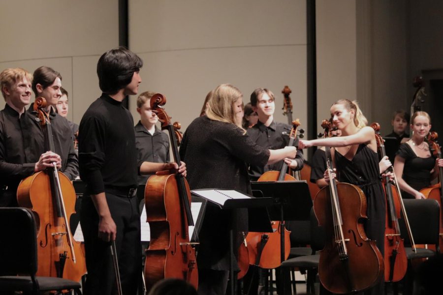Orchestra Director Megan Stucky-Swanson fist bumps Greta Stanier 23 after her solo in Memoirs, a piece commissioned for her and the other senior cellists