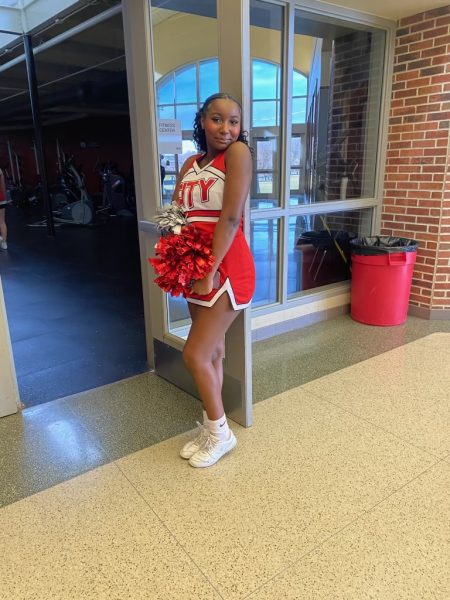 Breniah Richardson 26 poses for a picture in her cheerleading uniform in front of the old weight room. Photo courtesy of Richardson
