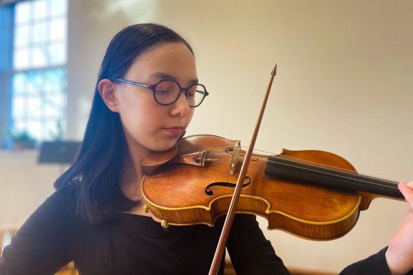 Tai Caputo ‘25 plays her violin in the orchestra room at City