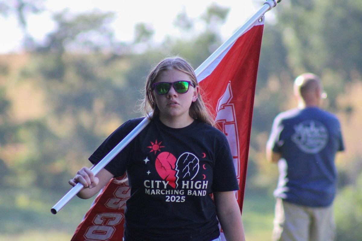 Harper Bailey '26 represents City High Cross Country with the team's flag.